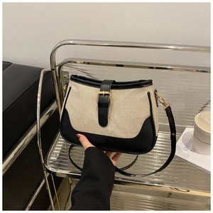 Detail of color-block canvas handbag with black leather trim and gold metal square buckle