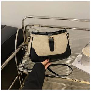 Detail of canvas shoulder bag with black leather strap and golden buckle accent