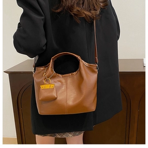 Detailed shot of brown leather bucket bag with litchi texture and mini lipstick pouch