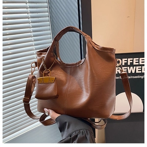 Macro detail of brown PU leather bucket bag with litchi texture and mini decorative pouch