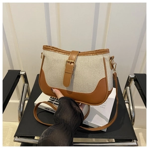 Detail of canvas and PU leather saddle bag featuring gold metal buckle and brown trim
