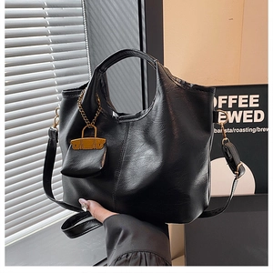 Close-up of black PU leather bucket bag with mini envelope charm and gold chain details