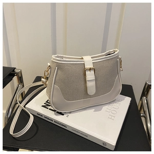 Detail of cream canvas crossbody bag with white leather trim and gold metal buckle