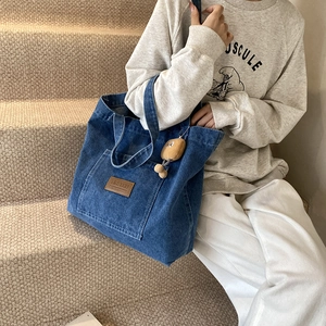 Sac cabas en jean bleu foncé avec logo en cuir et charm peluche sur la bandoulière