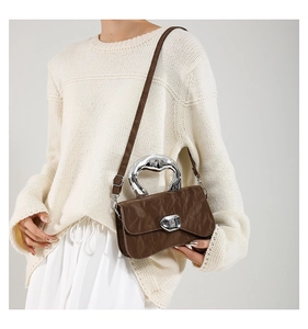 Detail showing deep brown pleated bag with silver liquid-metal handle and adjustable strap