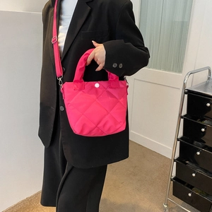 Pink quilted bucket bag with crossbody strap shown on model in black suit