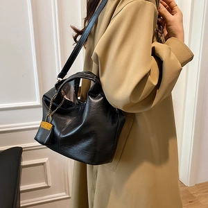 Minimalist black leather bucket bag with top handles and adjustable strap for women