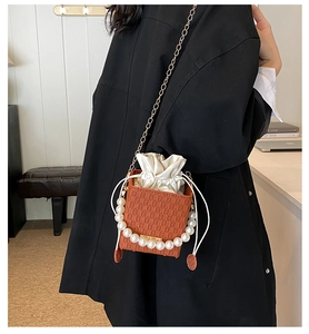 Detail of orange square crossbody bag featuring grid texture and pearl handle
