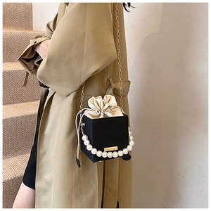 Detail der schwarzen Box-Tasche mit weißem Kunstperlengriff und goldener Kette