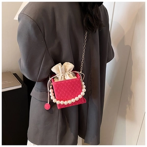 Dettaglio della borsa a tracolla fucsia a scacchi con manico di perle indossata da modella