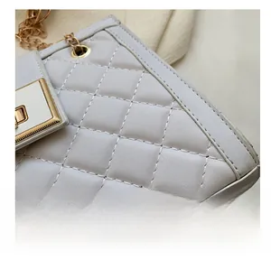 Close-up of quilted light gray crossbody bag showing white stitching and gold hardware