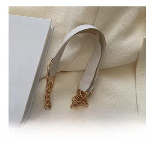 Detail of white PU leather and double golden metal chain strap on textured handbag