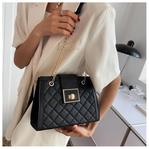 Close-up of black quilted crossbody bag with elegant gold chain strap and square lock
