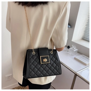 Detail of black quilted crossbody bag with gold chain strap and metal twist lock closure