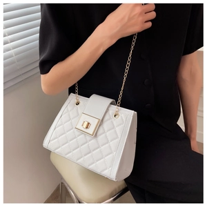 Detail of white quilted texture and golden twist lock on stylish crossbody bag