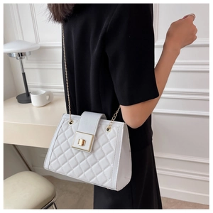 Detailed view of a white quilted crossbody bag with golden chain and square twist lock
