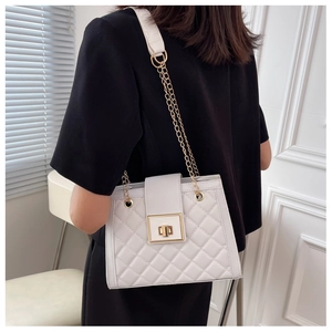 Detail of white quilted crossbody bag with gold rotating lock and chain strap on model