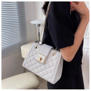 Close-up of white quilted crossbody bag with gold chain strap and metal swivel lock