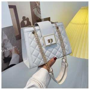 Detail of white quilted crossbody bag featuring a golden twist lock and chain strap