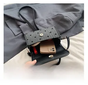 Internal view of mini black bag with polka dot flap showing phone and cosmetics storage