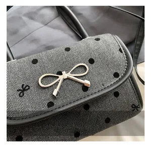 Detail showing the golden bow metal clasp and polka dot herringbone fabric of the handbag