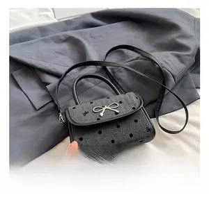 Detail view of small herringbone handbag with black polka dots and metallic bow clasp