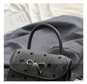 Detail of herringbone handbag with polka dots and silver metal bow buckle closure