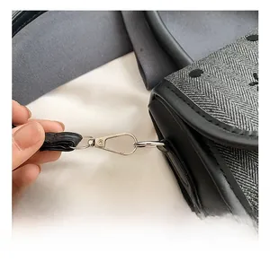 Detailed view of silver metal hooks and black leather straps on a grey polka dot bag
