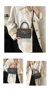 Detail of grey square handbag with bow pattern and silver metal bow clasp feature