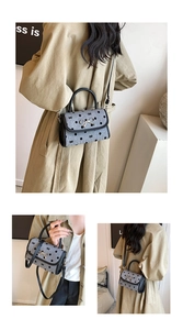 Detail of grey polka dot handbag with bow patterns and golden metallic bow hardware