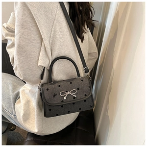 Close-up of small polka dot handbag with silver bow clasp and adjustable shoulder strap