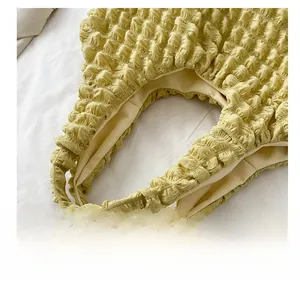Detail showing the mustard yellow bubble textured fabric and wide shoulder strap of the bag