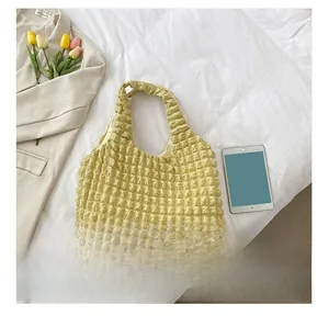 Detail showing bubble pleated texture and soft handle on a light yellow bucket bag