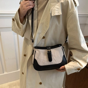 Chic cream canvas and black leather shoulder bag styled on a beige trench coat