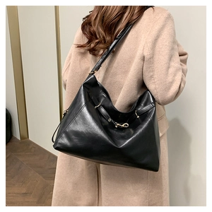 Model wearing a large black retro shoulder bag with adjustable strap and soft leather finish