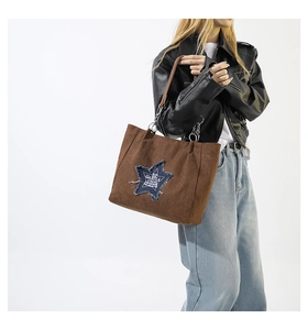 Close-up of star patch with frayed edges and logo detail on brown suede tote bag