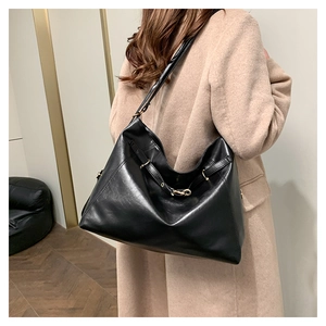 Detail of black leather hobo bag with adjustable metal buckle and slender shoulder strap