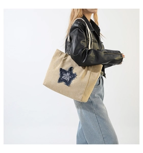 Detail of beige canvas tote bag featuring navy star patch and white rope handles