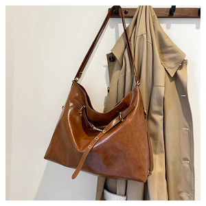 Detail of vintage caramel leather tote bag with metal eyelet strap on wooden hanger