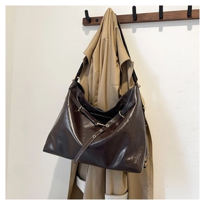 Detailed macro view of dark brown wax leather texture and golden metal eyelets on tote bag