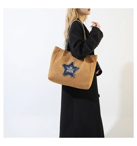 Detailed close-up of large brown corduroy tote bag with blue denim star patch on shoulder