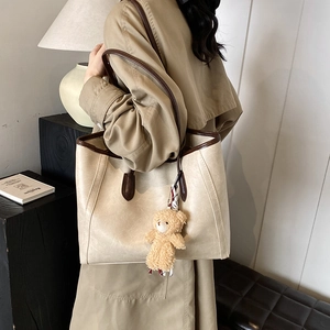 Chic beige tote bag with brown trim and plush bear charm for autumn fashion women