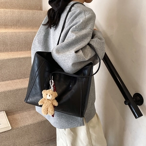 Black large capacity faux leather tote bag with cute bear charm on female model
