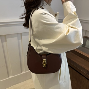 Braune Halbmond-Schultertasche aus Leder mit goldener Schnalle an einem Modell gezeigt