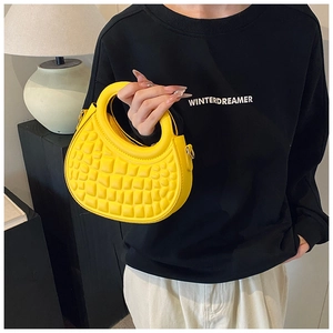 Detail of bright yellow semi-circle handbag with embossed square texture on PU leather