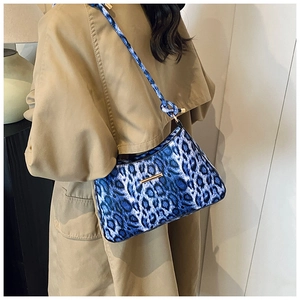 Dettaglio borsa hobo blu leopardata con decoro dorato indossata con un trench beige