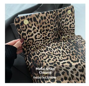 Close-up of leopard print handbag showing golden magnetic buckle and chain detail