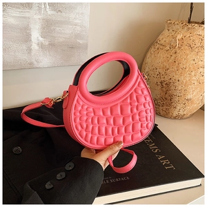 Detail of pink crescent bag with crocodile pattern and unique hollow round handle