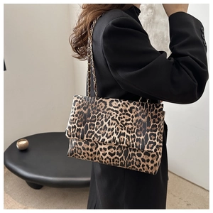 Detail of leopard print shoulder bag with golden chain strap on a black blazer
