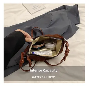Internal capacity of brown suede dumpling bag showing makeup storage and knotted strap